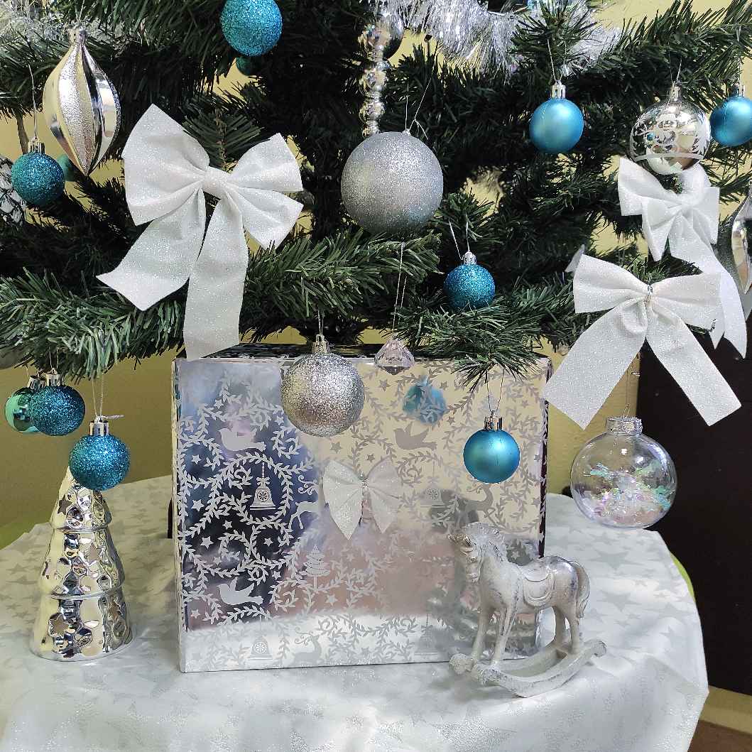 Kék-ezüst karácsonyi díszek, fehér masnik és díszdoboz a fa alatt
